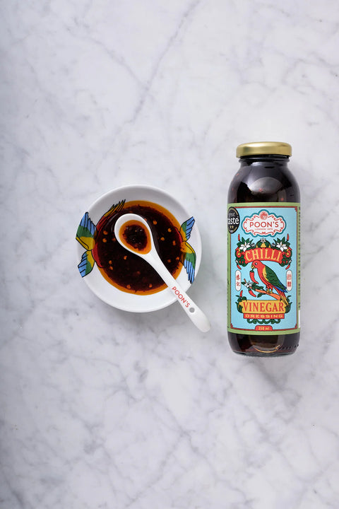 bottle of vinegar next to bowl of chilli vinegar on marble counter