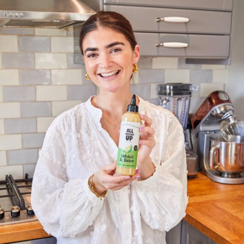all dressed up tahini and lime dressing being held by the owner