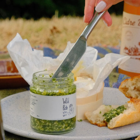 a person about to spread pesto from jar of wild garlic pesto 