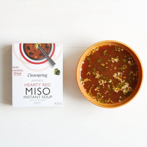 Clearspring Hearty Red Miso Instant Soup packaging next to a bowl of soup on a white background