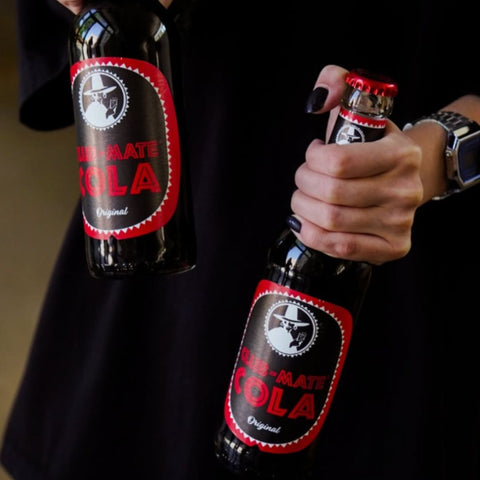 person holding 2 bottles of club mate cola 330ml