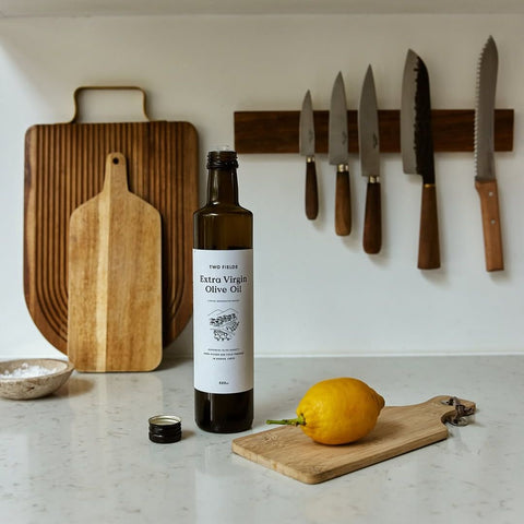 two fields olive oil on a kitchen counter next to a lemon 