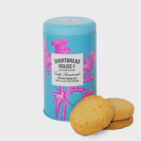 Shortbread house clotted cream tin with biscuits in front in pile 