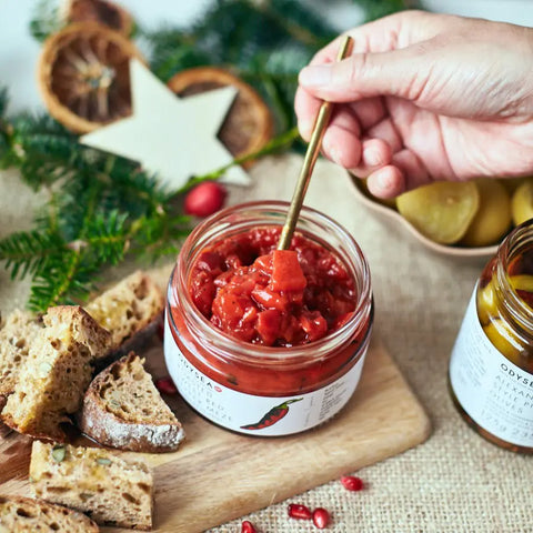 jar of meze with spoon scooping it out next to bread on a wooden surface