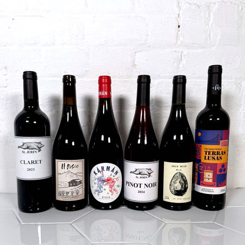 6 bottles of red wine in front of a white wall