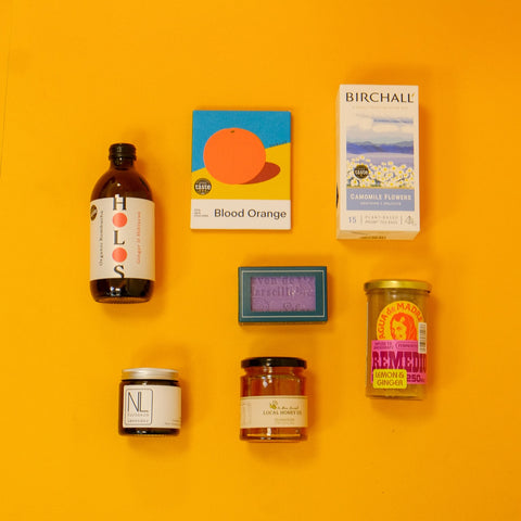 Collection of various wellness food products including a bottle, jars, and boxes on a yellow background