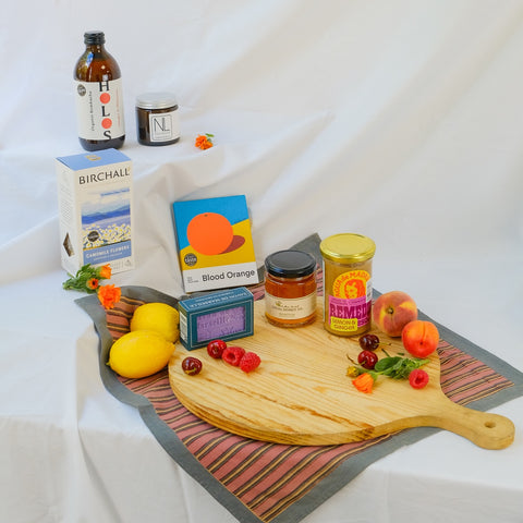 Wooden cutting board with fruits, a bottle, and boxes on a white background