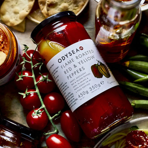 jar of red and yellow peppers with crackers, tomatoes, and various other food