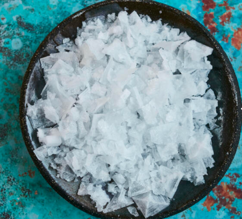 bowl of salt flakes on a blue surface
