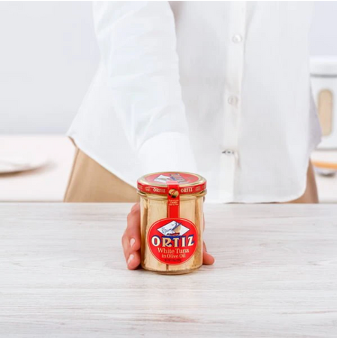 hand holding jar of ortiz on wooden table