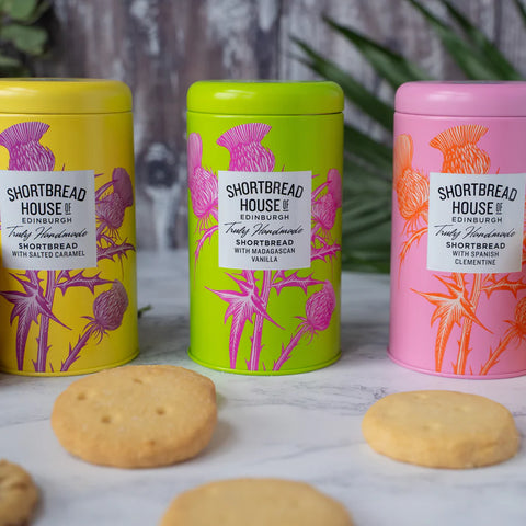 Three tins of shortbread with biscuits in front