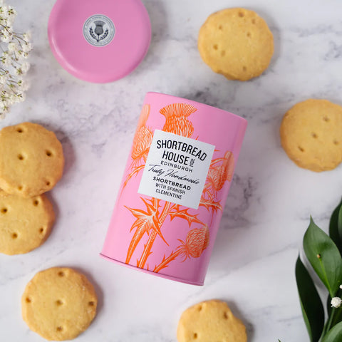 Clementine shortbread tin on it's back with biscuits around it