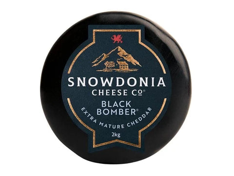 A round black cheese wheel with a dark blue and gold label reading 'Snowdonia Cheese Co Black Bomber Extra Mature Cheddar 2kg' on a white background.