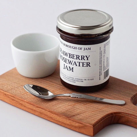 chopping board with jar of strawberry jam on it