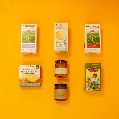Collection of teas and other food products including boxes and jars on a yellow background