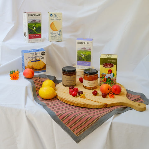 Wooden cutting board with jars, fruits, and boxes on a white fabric background