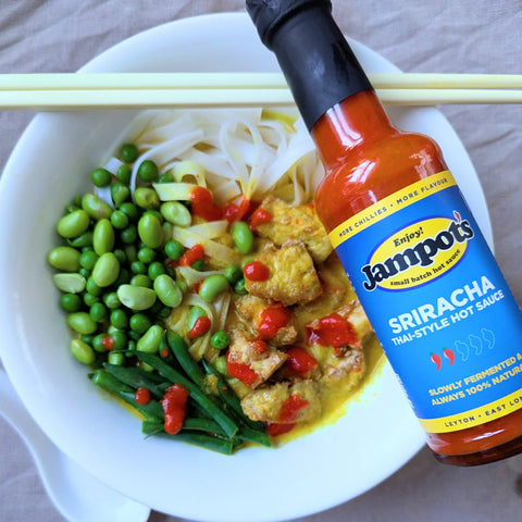 bottle of sauce on a bowl with food and chopsticks
