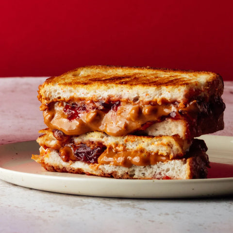 peanut butter and jelly sandwich on a plate with a red background