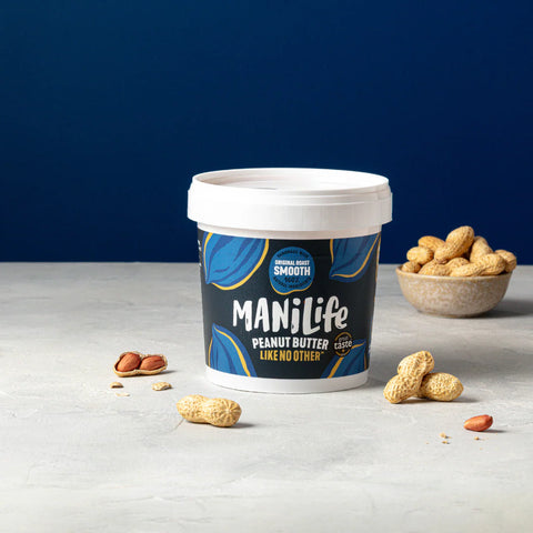 container of original roast smooth peanut butter with peanuts scattered around on white surface with blue background