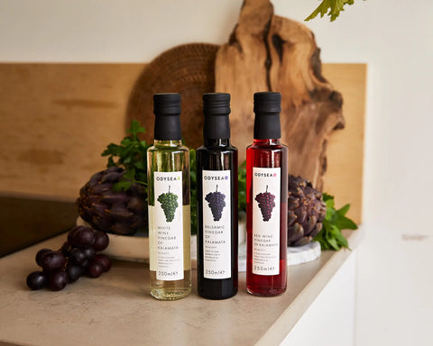 multiple bottles of vinegar on counter with wood in background