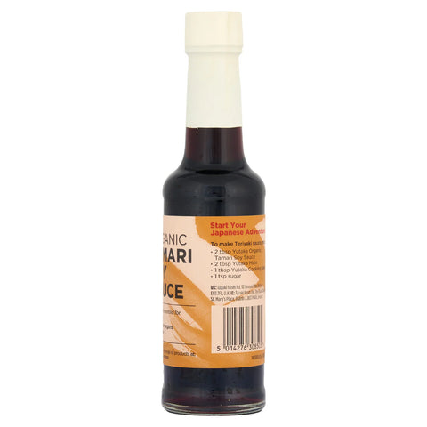 A bottle of organic tamari soy sauce with a white cap and a brown and orange label, shown against a plain white background.