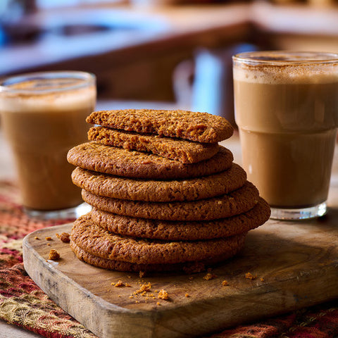 stack of yorkshire parkin biscuits on a wooden cutting board next to a glass of coffee