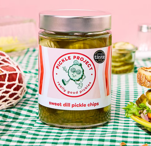Jar of Pickle Project sweet dill pickle chips on a checkered tablecloth with a pink background