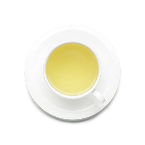 White cup and saucer with yellow liquid on a white background