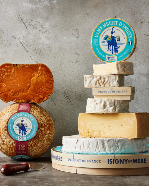 Assorted cheeses with Camembert d'Isigny labels on a gray surface