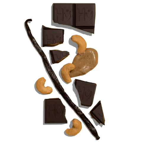 pieces of chocolate bar, cashews, and vanilla bean on white background