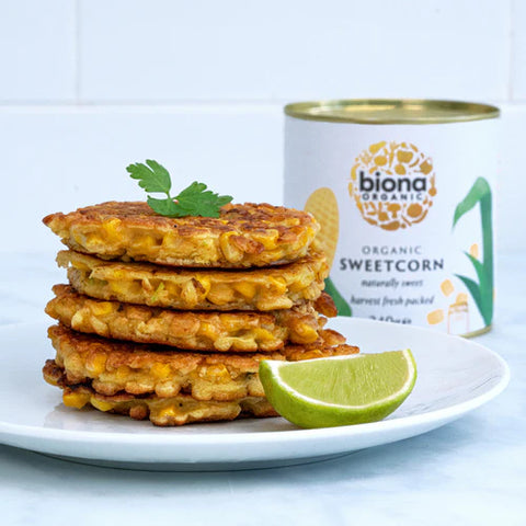 Stack of corn fritters on a plate with a can of biona organic sweetcorn in the background.