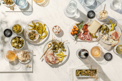 table set with plates and bowls of food with multiple jars of perello