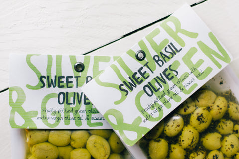 two bags of the sweet basil olives on a white wooden surface